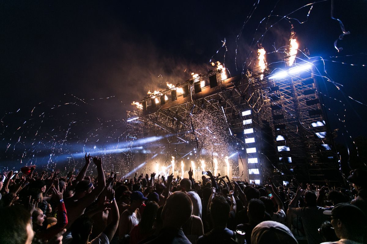 Concert crowd facing a stage with purple lights and stage effects.
