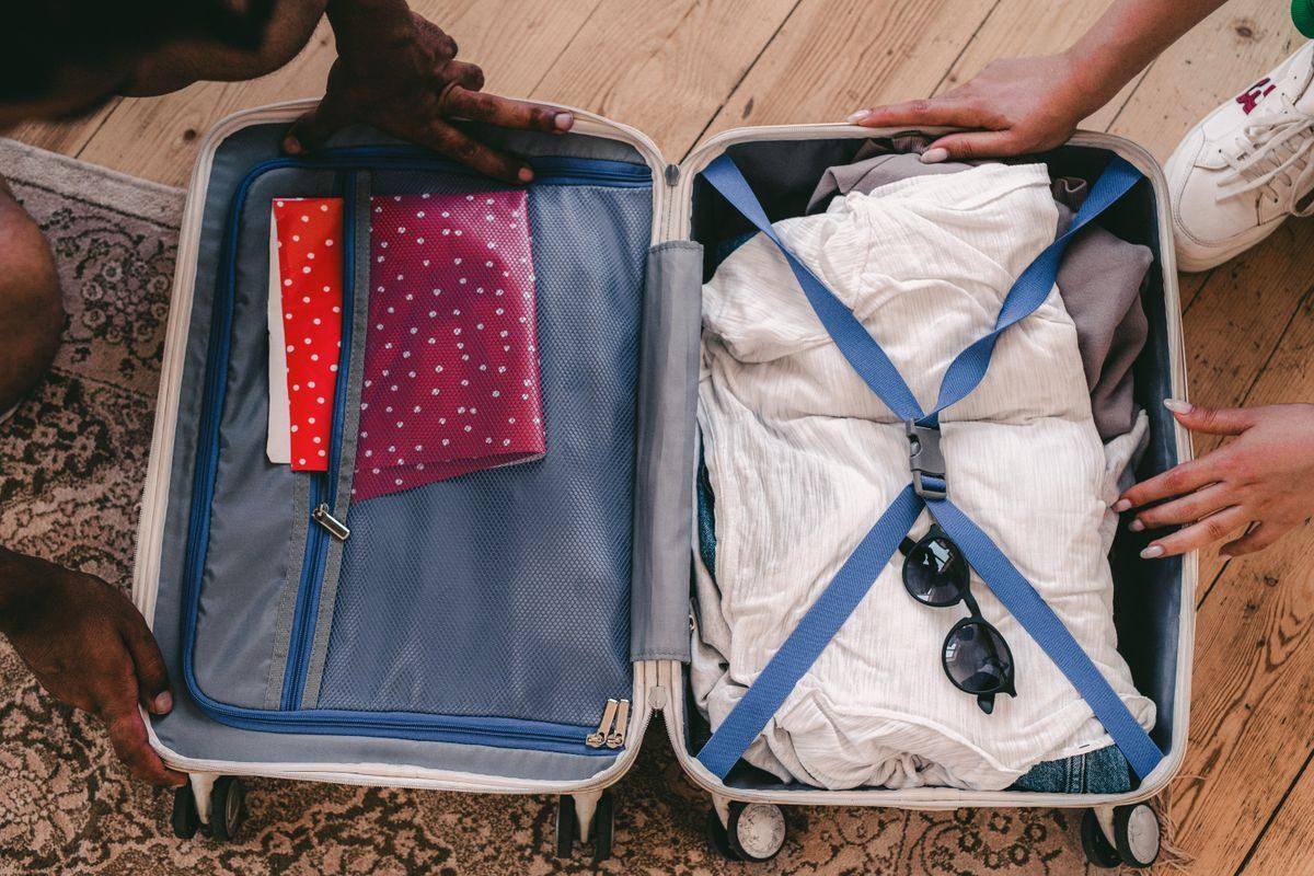 Open suitcase packed with clothes and sunglasses.