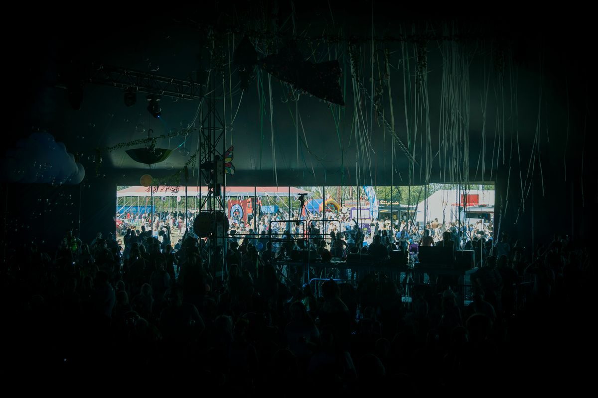 Crowd watching a concert stage in a large covered venue.